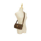 Manequim utilizando a Bolsa Baguete Sophia marrom no estilo transversal (crossbody), demonstrando o caimento e a proporção da bolsa no corpo. Preto Caramelo Off White Marrom