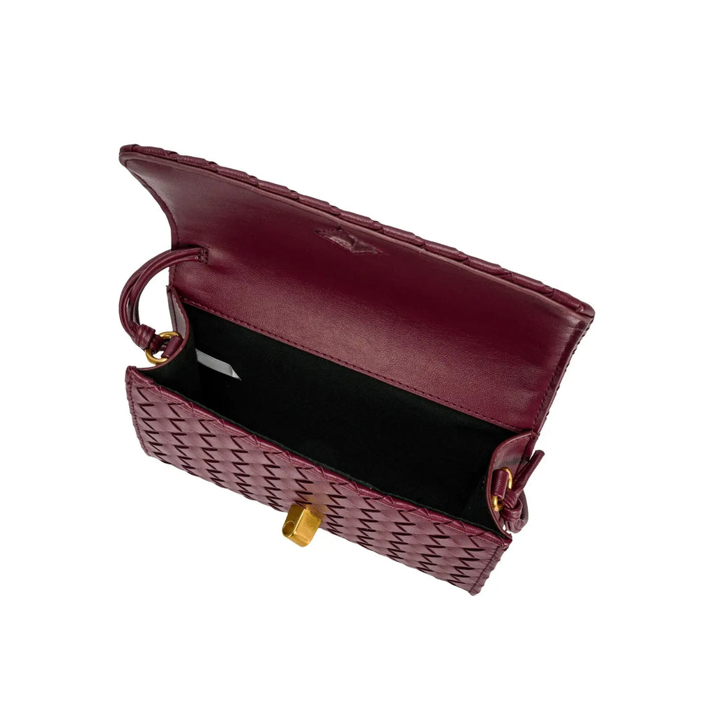 Vista superior da bolsa clutch Diana vinho aberta, revelando o compartimento interno com forro escuro e o sistema de fecho dourado. Preto Bordô