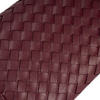 Imagem em macro focada no detalhe do trançado tressê na cor vinho da bolsa clutch Diana, mostrando de perto a padronagem e a qualidade do material. Preto Bordô