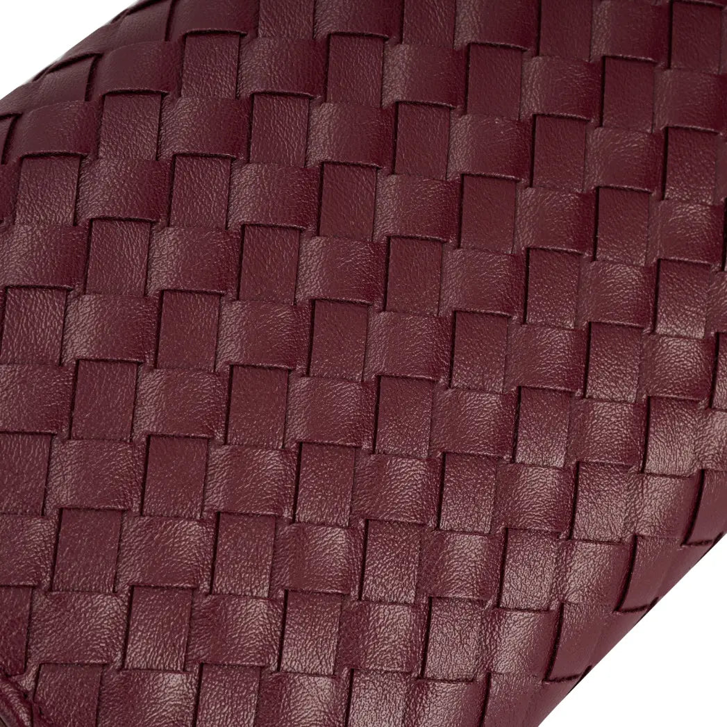 Imagem em macro focada no detalhe do trançado tressê na cor vinho da bolsa clutch Diana, mostrando de perto a padronagem e a qualidade do material. Preto Bordô