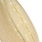Detalhe em macro da textura inteiramente cravejada de mini cristais da bolsa clutch Melissa dourada e da dobradiça metálica inferior. Preto Dourado
