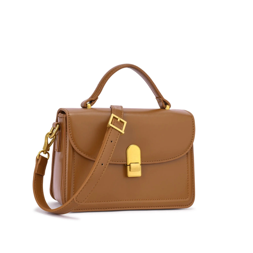 Bolsa de mão Livia estruturada na cor caramelo, vista frontal em ângulo exibindo a alça de ombro longa sobreposta, alça de mão superior e ferragens douradas. Preto Caramelo Off White Vermelho