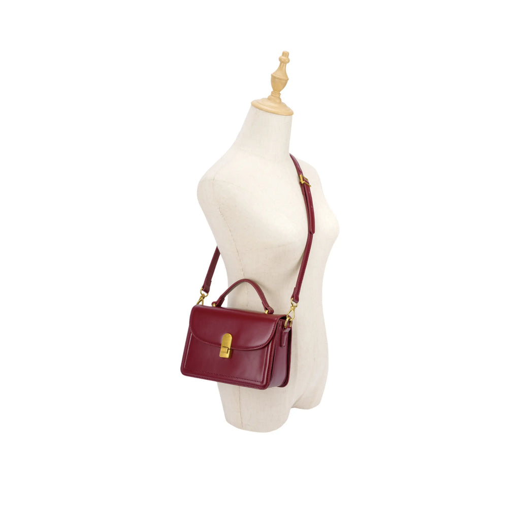 Manequim utilizando a bolsa de mão Livia estruturada na cor vinho na posição transversal (crossbody), demonstrando a proporção, o caimento e a versatilidade do uso no corpo. Preto Caramelo Off White Bordô