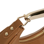 Close-up das ferragens douradas de alta qualidade da bolsa hobo meia lua Marianne caramelo, conectando o corpo da bolsa à alça metálica rígida e à argola da alça longa transversal. Preto Caramelo Off White