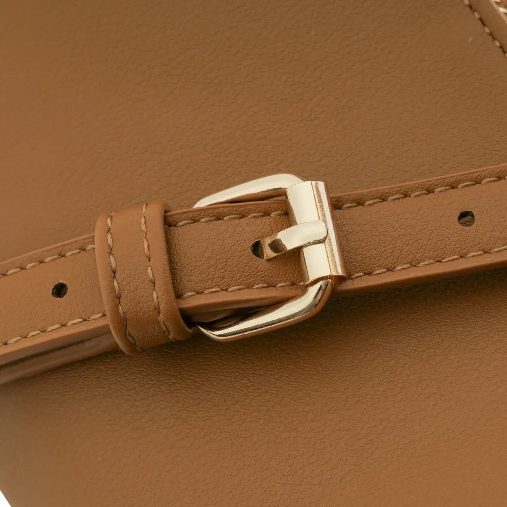 Detalhe em macro da fivela metálica dourada de ajuste na alça transversal da bolsa hobo meia lua Marianne caramelo, mostrando as costuras precisas no material. Preto Caramelo Off White