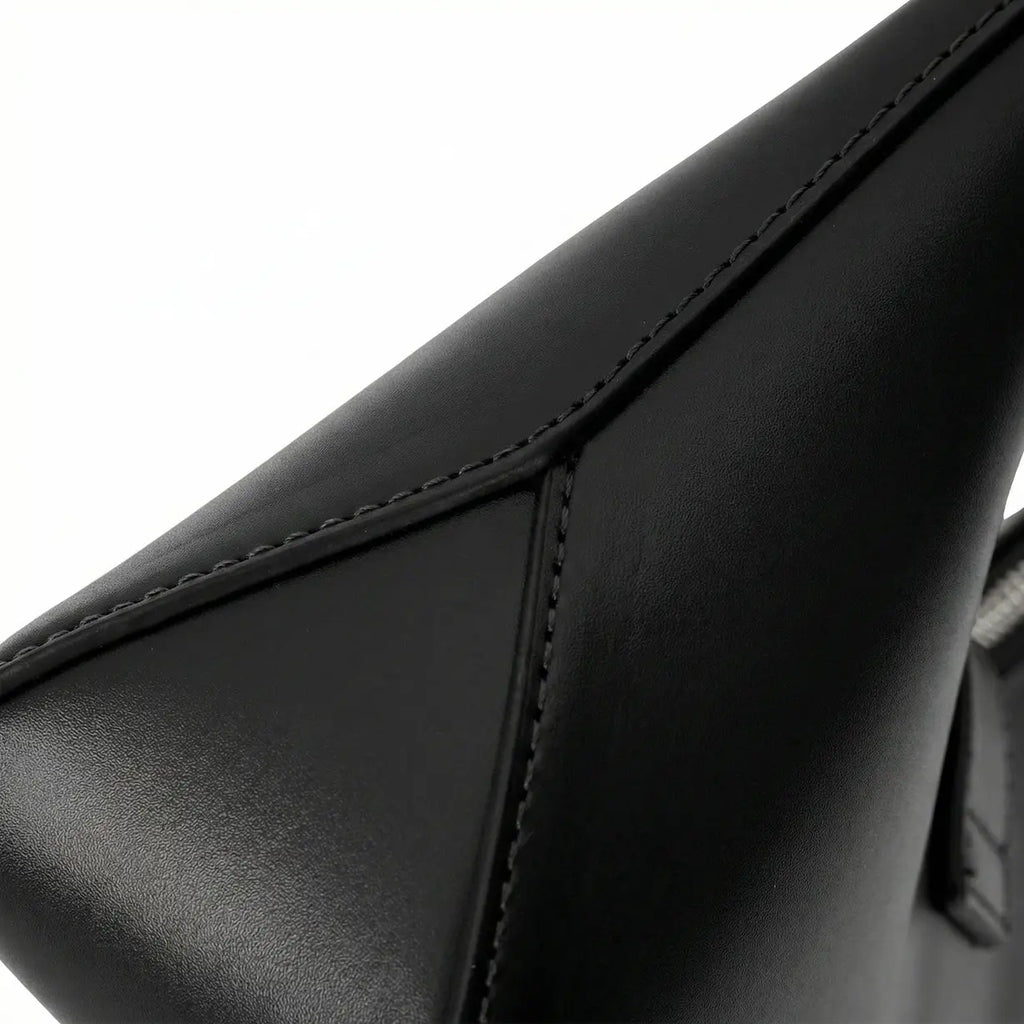 Detalhe em macro da bolsa hobo Talessa preta, evidenciando a textura sofisticada do material e a alta qualidade do acabamento geométrico nas costuras laterais.