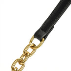 Close-up da junção da alça de material sintético preto com a corrente de elos grossos dourados da Bolsa Baguete Vivianne. Preto [cor:Preto]