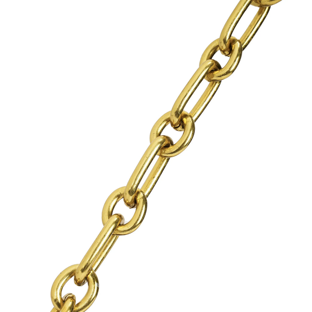 Detalhe em macro focando exclusivamente nos elos alongados da elegante corrente metálica dourada que compõe a alça da bolsa. Preto Caramelo Off White Marrom