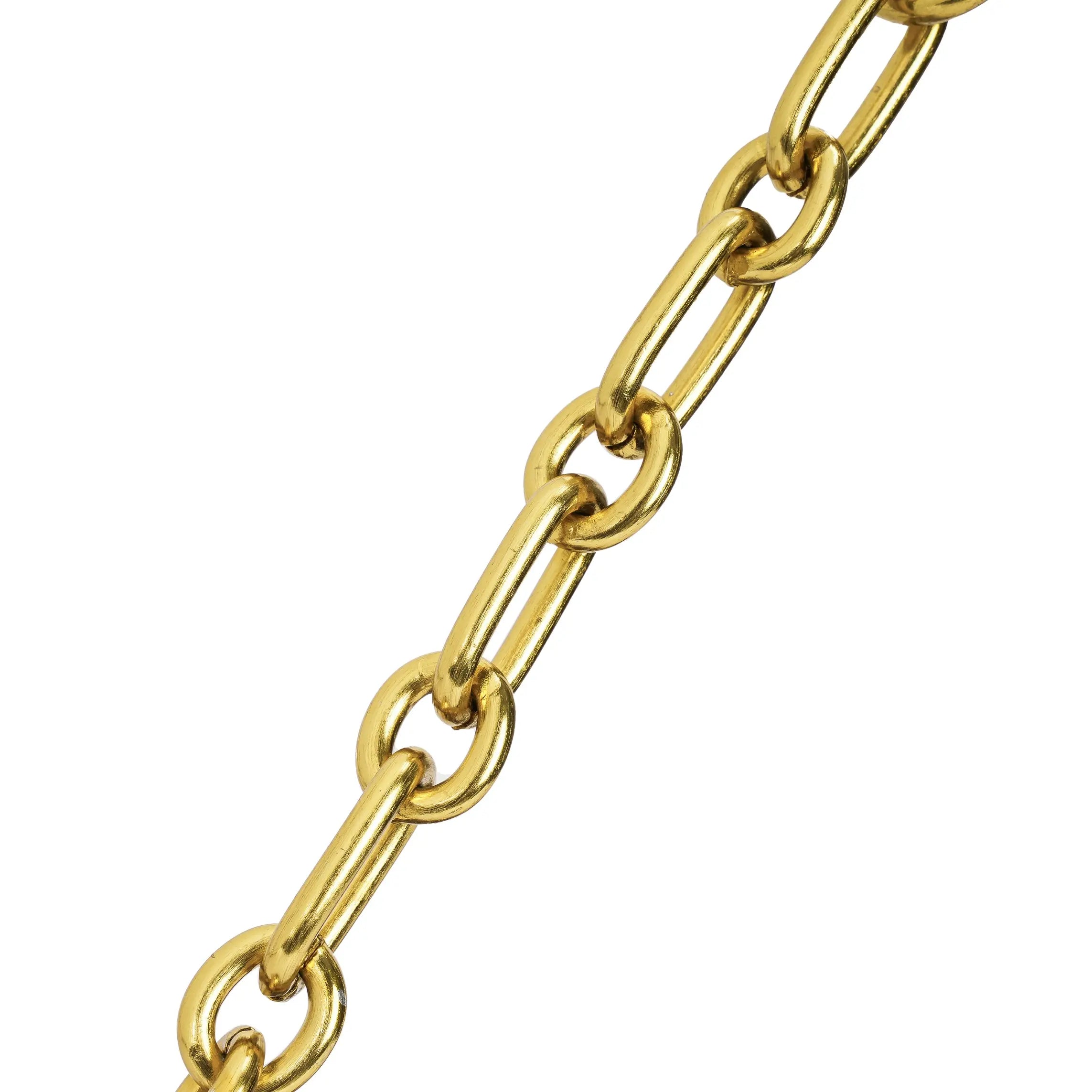 Detalhe em macro focando exclusivamente nos elos alongados da elegante corrente metálica dourada que compõe a alça da bolsa. Preto Caramelo Off White Marrom