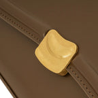 Detalhe em zoom do fecho magnético de metal dourado escovado na aba frontal da Bolsa Baguete Sophia marrom. Preto Caramelo Off White Marrom