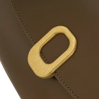 Detalhe em zoom do fecho metálico dourado com acabamento canelado em formato retangular na frente da Bolsa Baguete Clarissa marrom. Preto Caramelo Off White Marrom