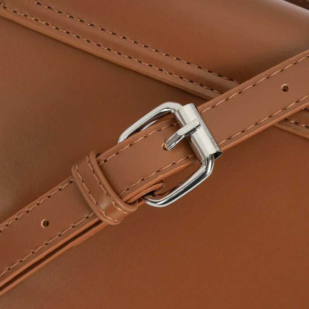 Detalhe macro da fivela prateada com passante para ajuste prático na alça de ombro da Bolsa Baguete Minimalista Isabele marrom. Preto Caramelo Off White Bege