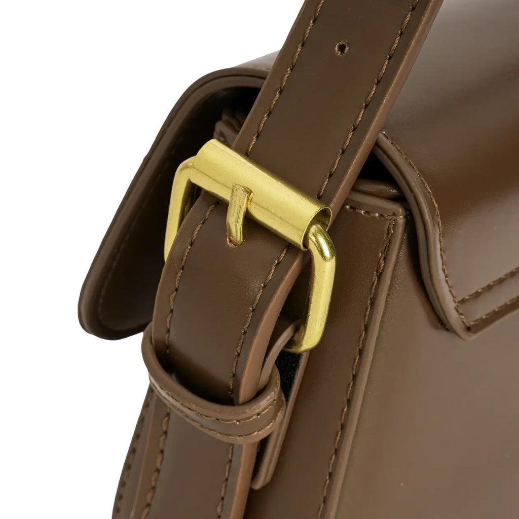 Detalhe aproximado da fivela dourada de ajuste de comprimento da alça, com costuras visíveis na lateral da bolsa marrom. Preto Caramelo Off White Marrom