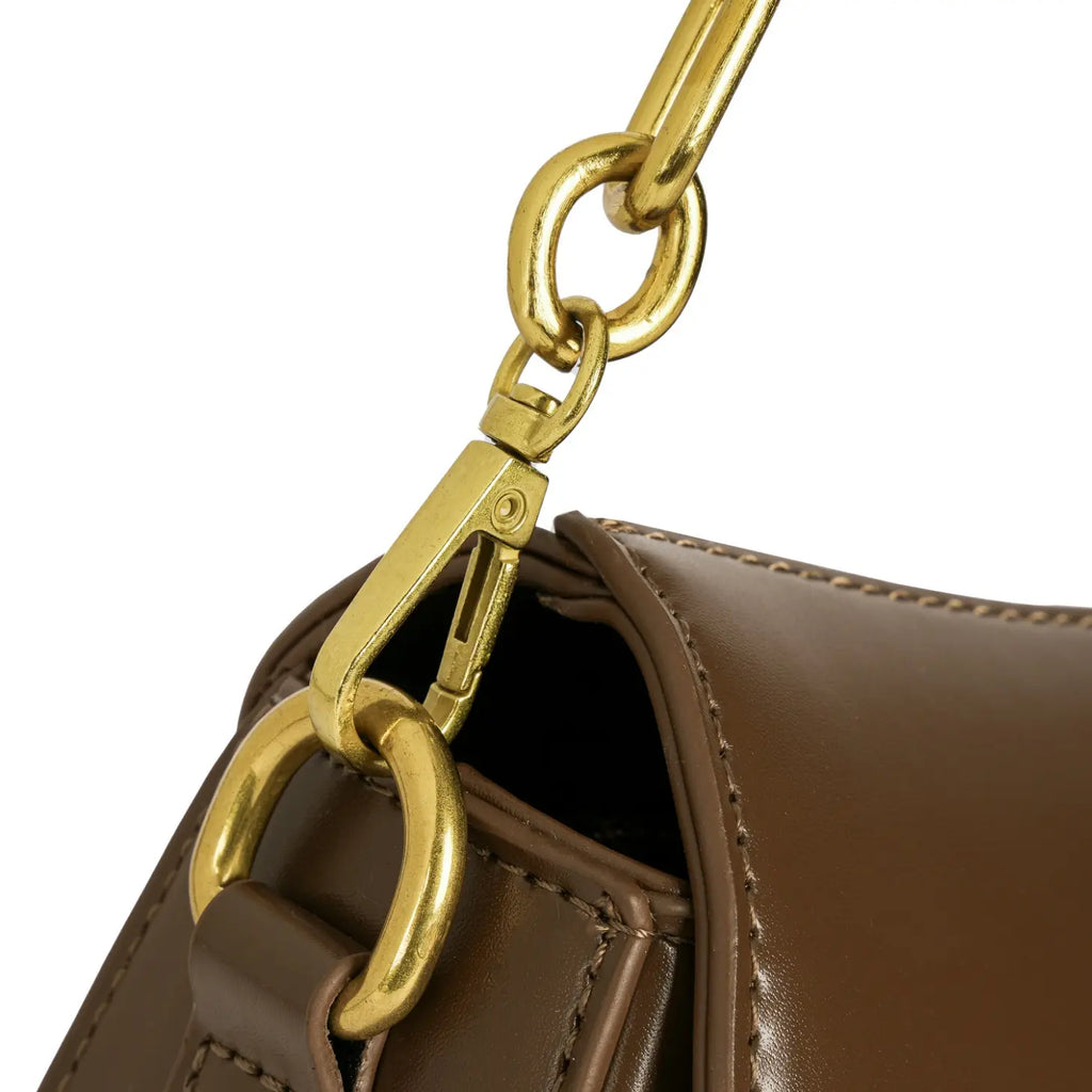 Detalhe aproximado do mosquetão metálico dourado conectando a alça à estrutura da Bolsa Baguete Clarissa marrom. Preto Caramelo Off White Marrom