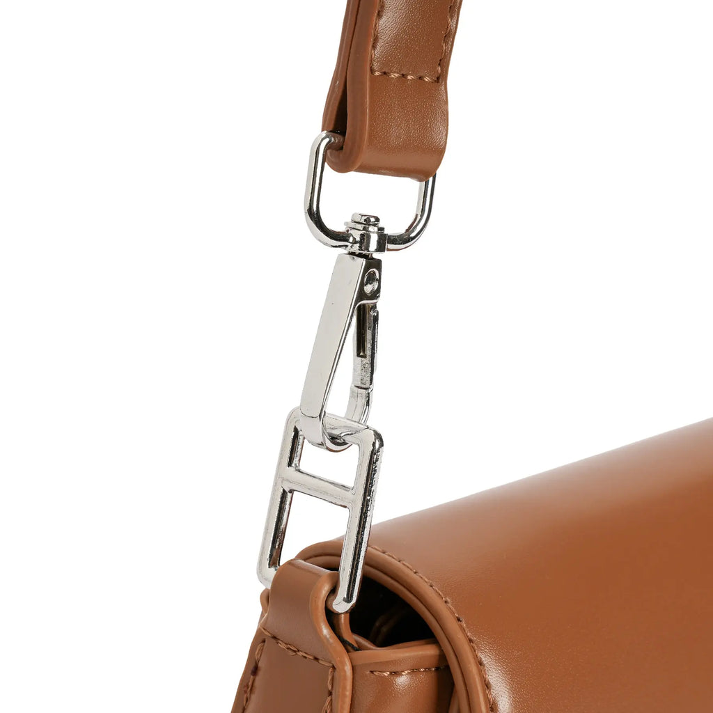 Detalhe do resistente mosquetão metálico prateado em formato retangular conectando a alça à estrutura de couro da bolsa marrom. Preto Caramelo Off White Bege