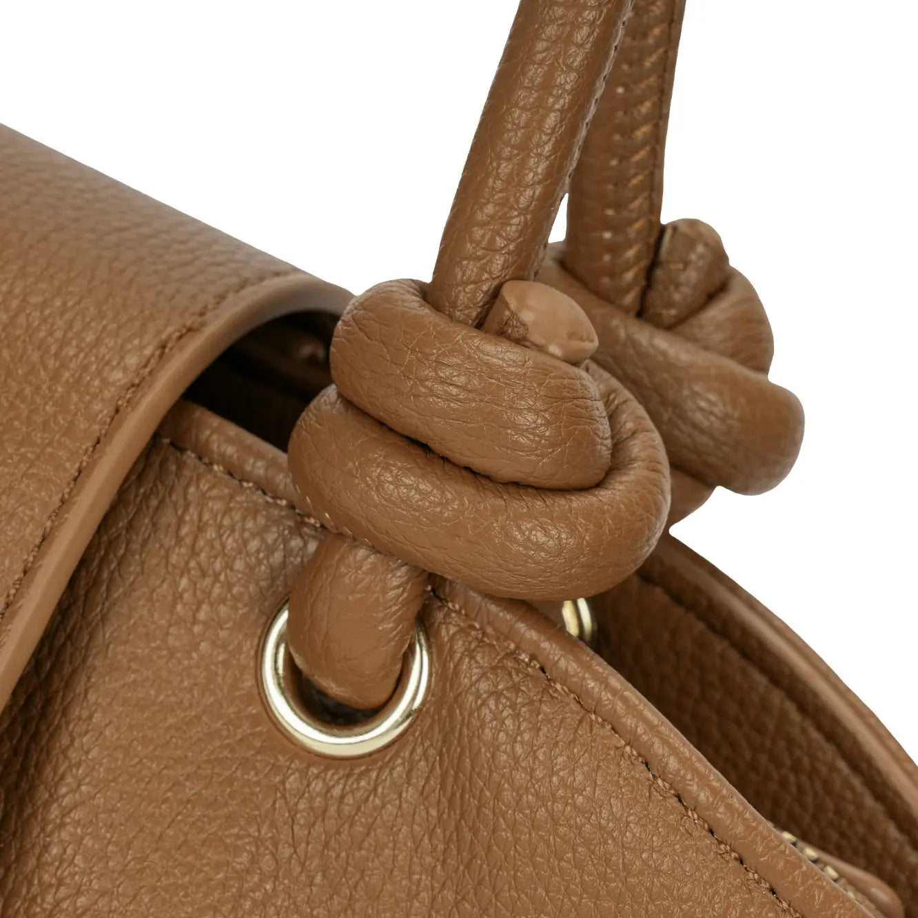 Detalhe macro do nó estruturado em couro na base da alça dupla da bolsa marrom, destacando a argola de metal dourado e o acabamento impecável. Preto Caramelo Off White