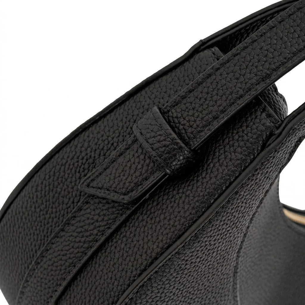 Detalhe em close da costura e do passador lateral da alça em material sintético texturizado da Bolsa Baguete Victoria preta. Preto [cor:Preto]