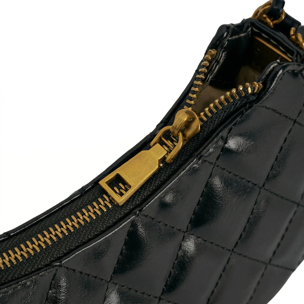 Close-up do zíper metálico dourado com puxador anatômico e acabamento premium da Bolsa Matelassê Amelia. Preto [cor:Preto]