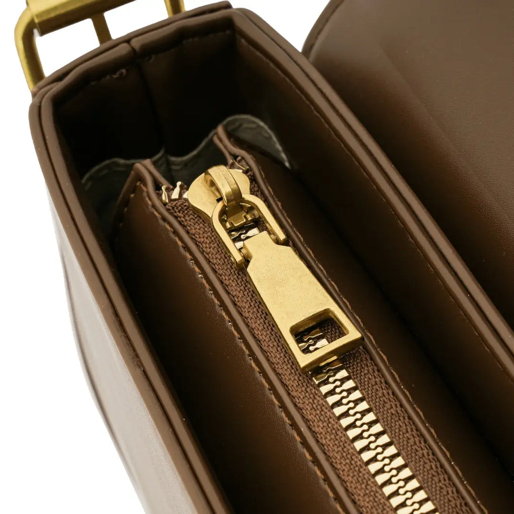 Detalhe macro do puxador metálico do zíper interno e do tecido do forro da Bolsa Baguete Sophia marrom. Preto Caramelo Off White Marrom