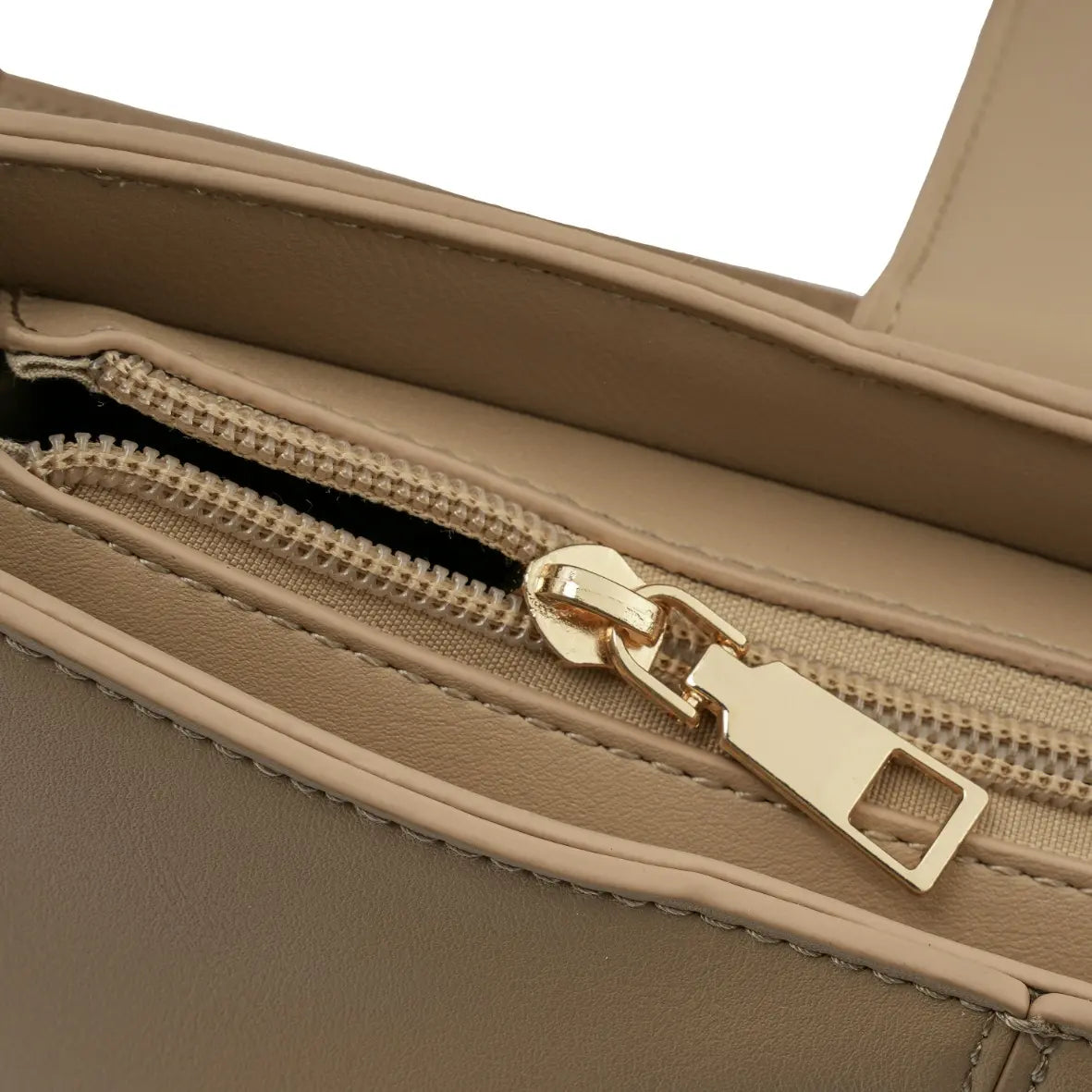 Detalhe macro do puxador do zíper dourado interno e do acabamento impecável do forro da Bolsa Hobo Louise bege. Preto Caramelo Off White Bege