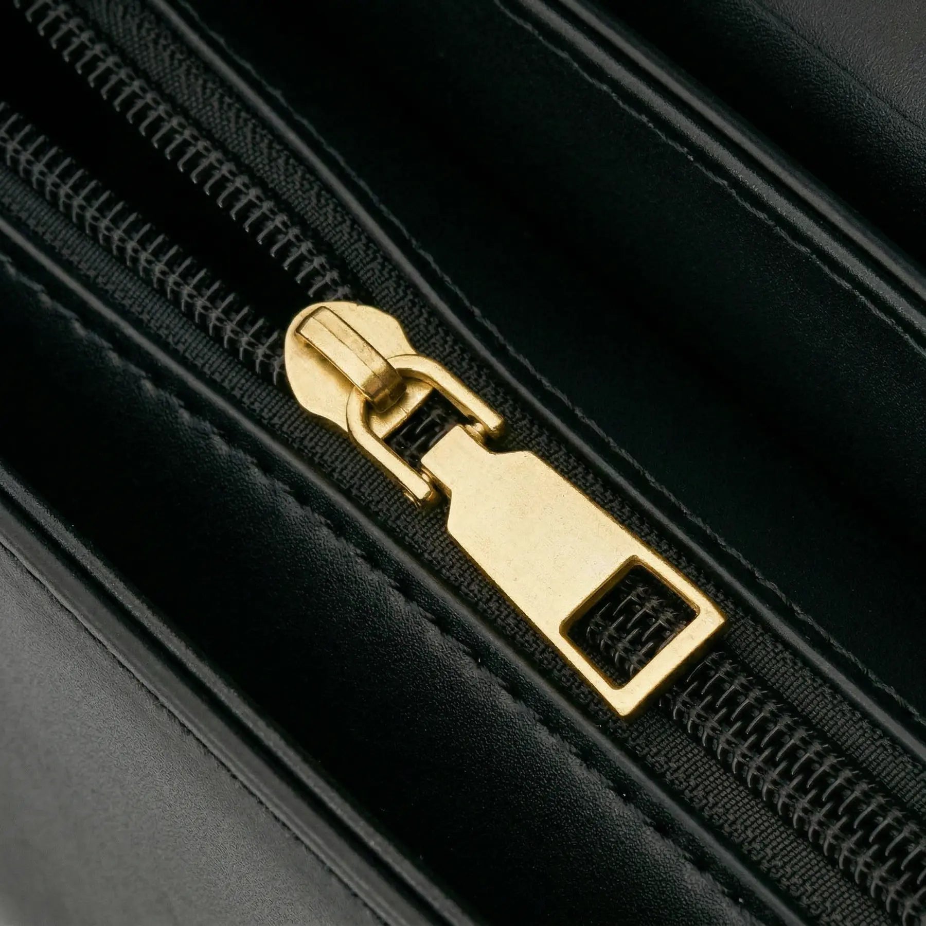 Detalhe em close do puxador de zíper metálico dourado e acabamento da costura interna da Bolsa Baguete Vivianne. Preto [cor:Preto]