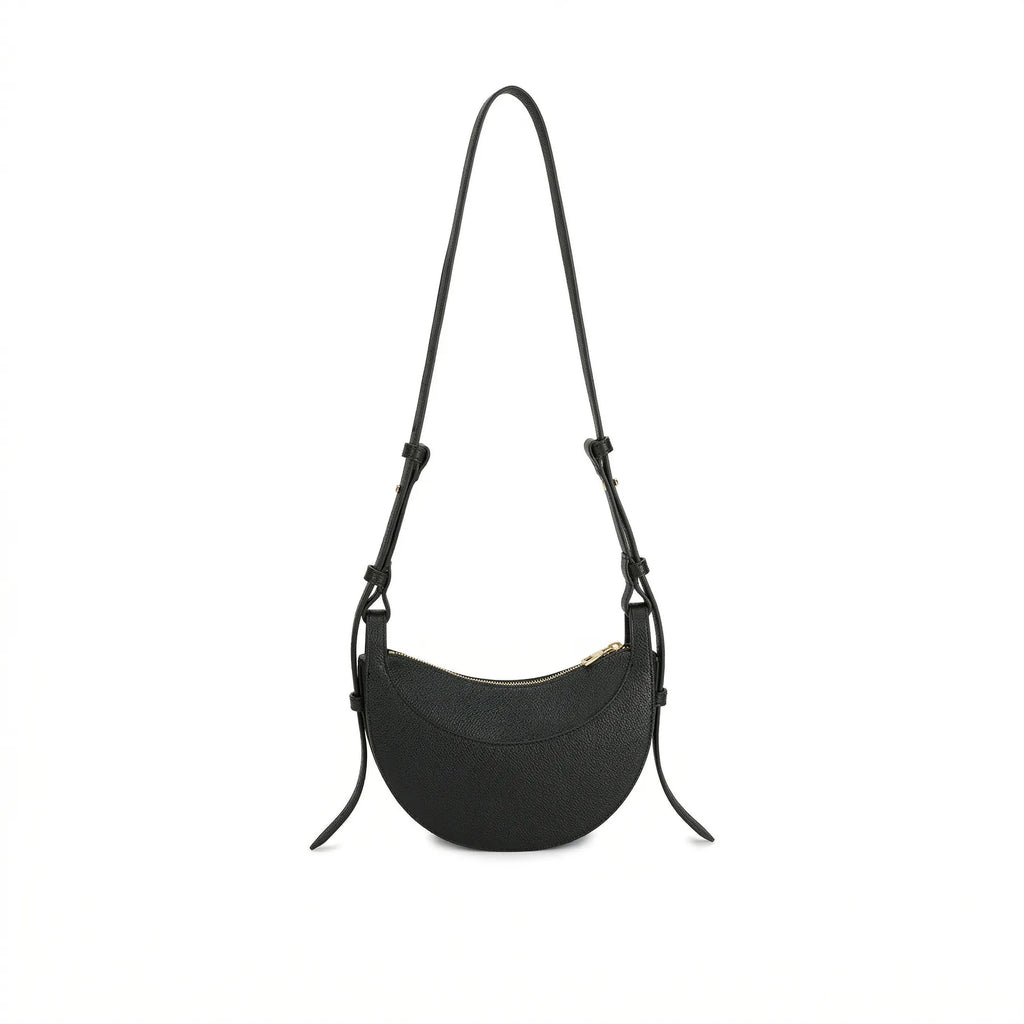 Visão traseira da Bolsa Baguete Victoria preta suspensa, destacando o design minimalista em formato crescente e a textura premium do material. Preto [cor:Preto]