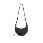 Visão traseira da Bolsa Baguete Victoria preta suspensa, destacando o design minimalista em formato crescente e a textura premium do material. Preto [cor:Preto]